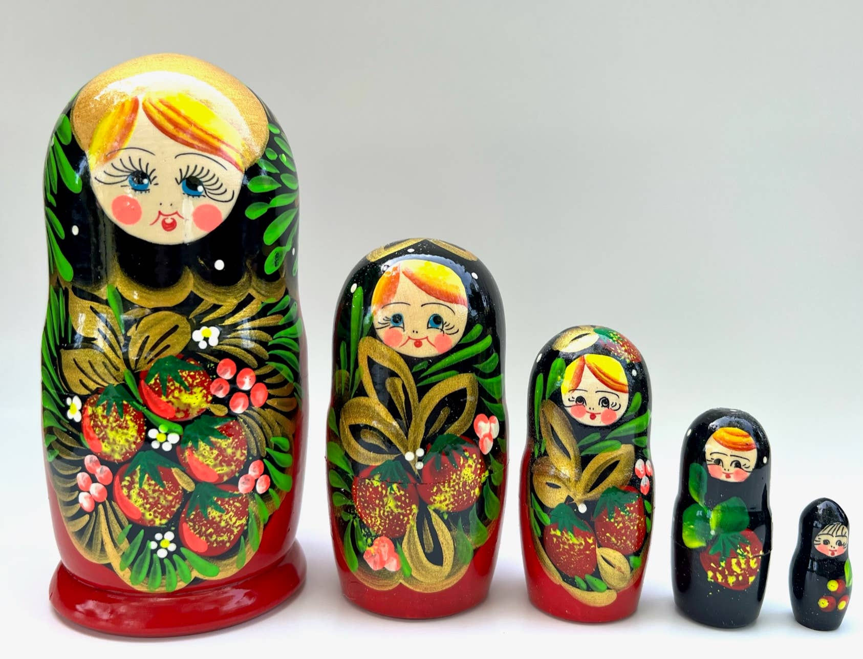 Nested Russian dolls in a row, with floral decorations and smiling faces.