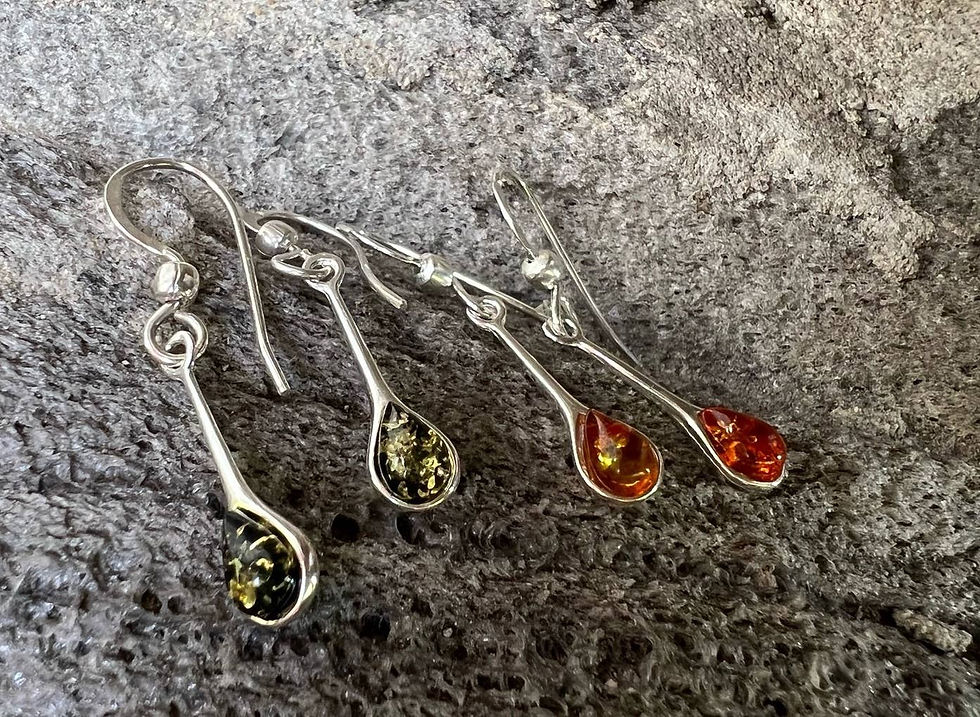 Four sterling silver earrings with amber colored teardrop pendants on display.