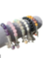 Various colorful beaded bracelets displayed on a gray cylindrical jewelry holder