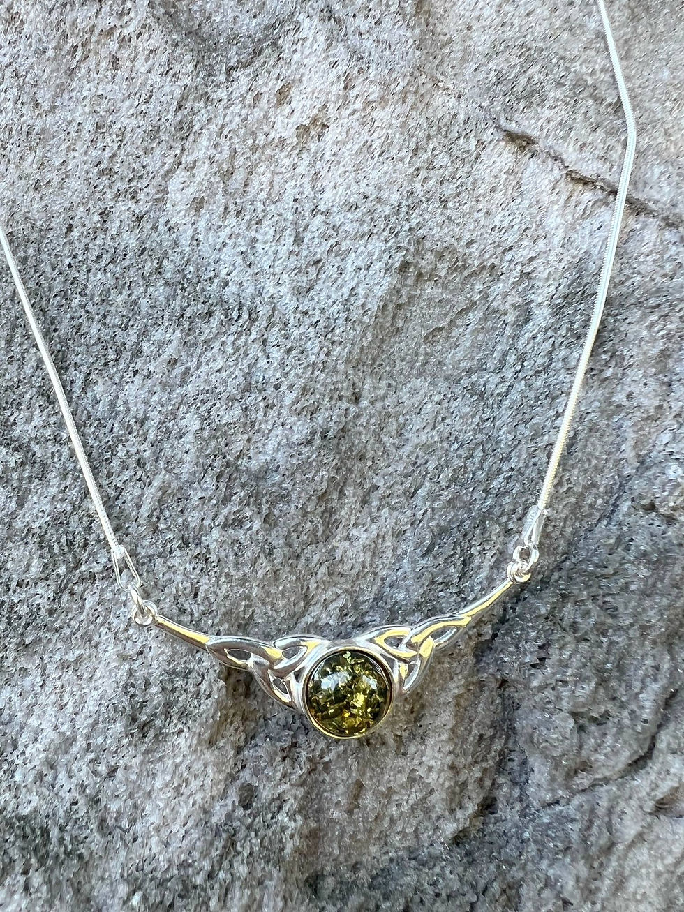 Thumbnail: Silver necklace with green gem on a grey rock background for sale