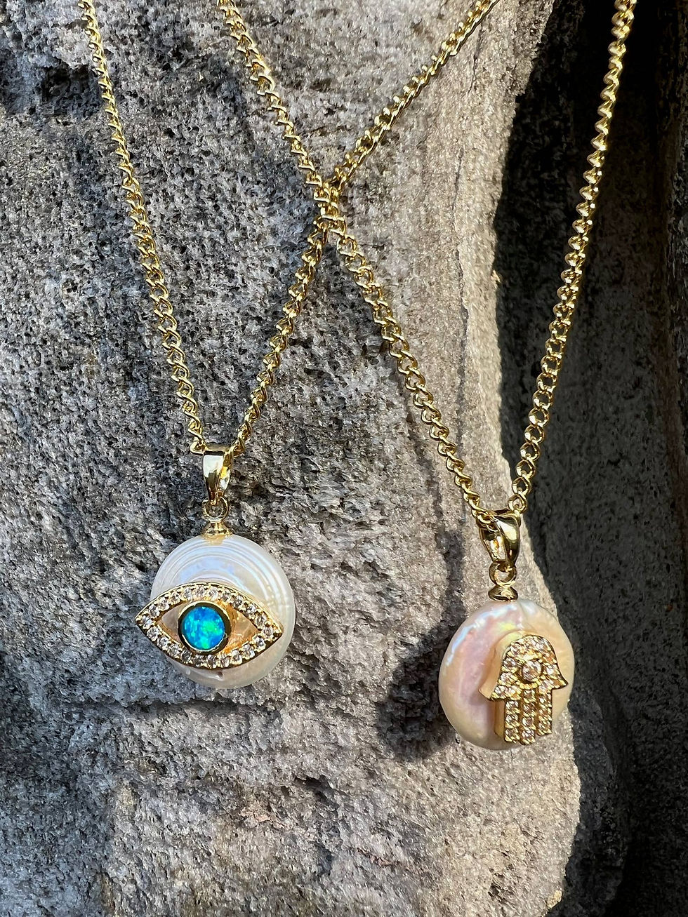 Thumbnail: Two gold necklaces with pearl pendants; eye and hand charms on display.
