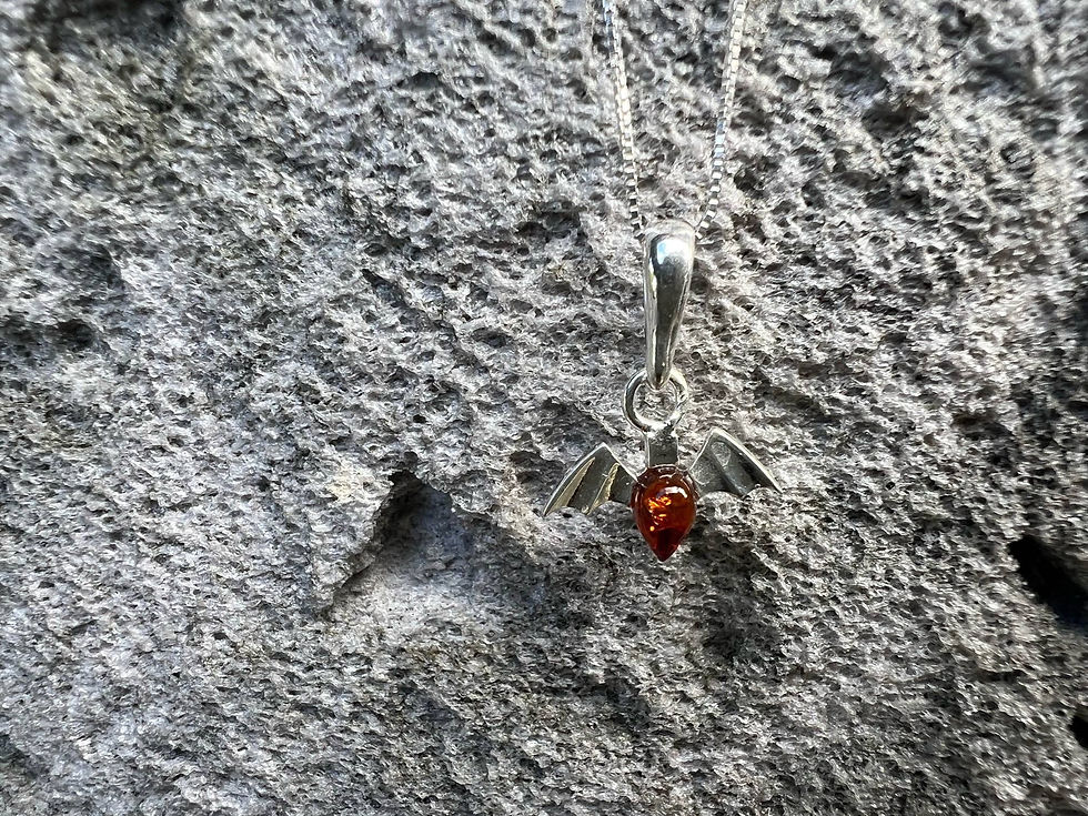 Thumbnail: Silver bat pendant with amber stone, displayed on a textured gray rock.