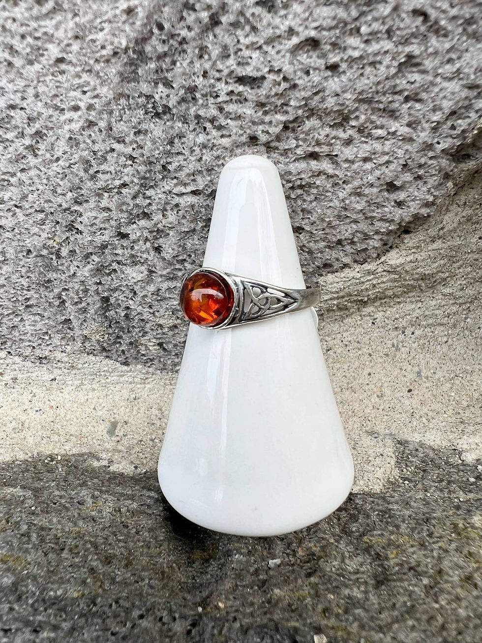 Silver ring with amber stone displayed on white ceramic cone outside.