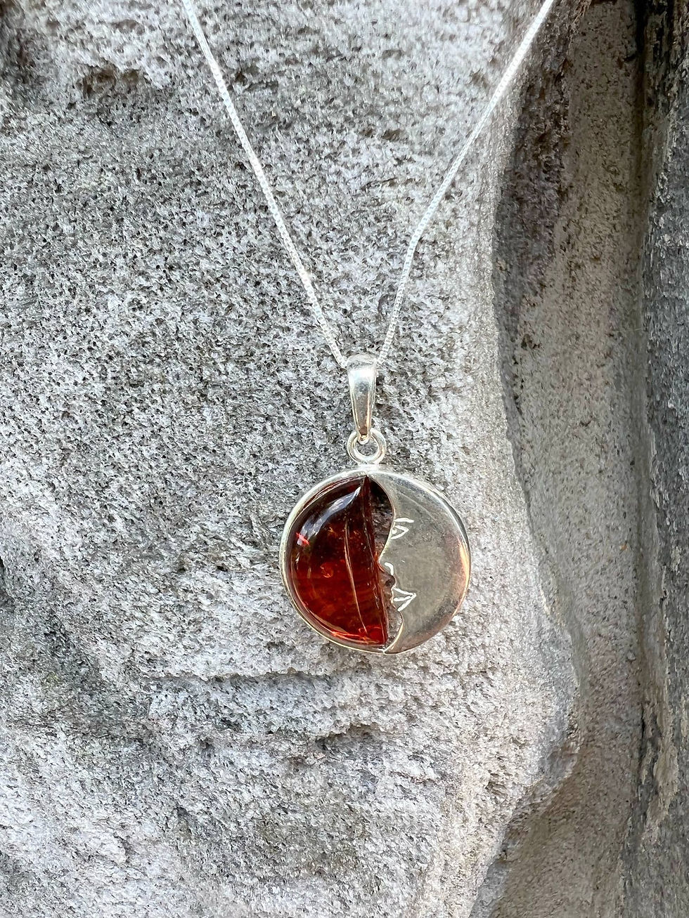 Thumbnail: Silver necklace with crescent moon pendant, red gemstone detail on gray rock
