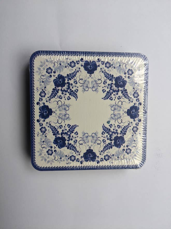 Square tin with blue floral design on white background, packaged for sale.