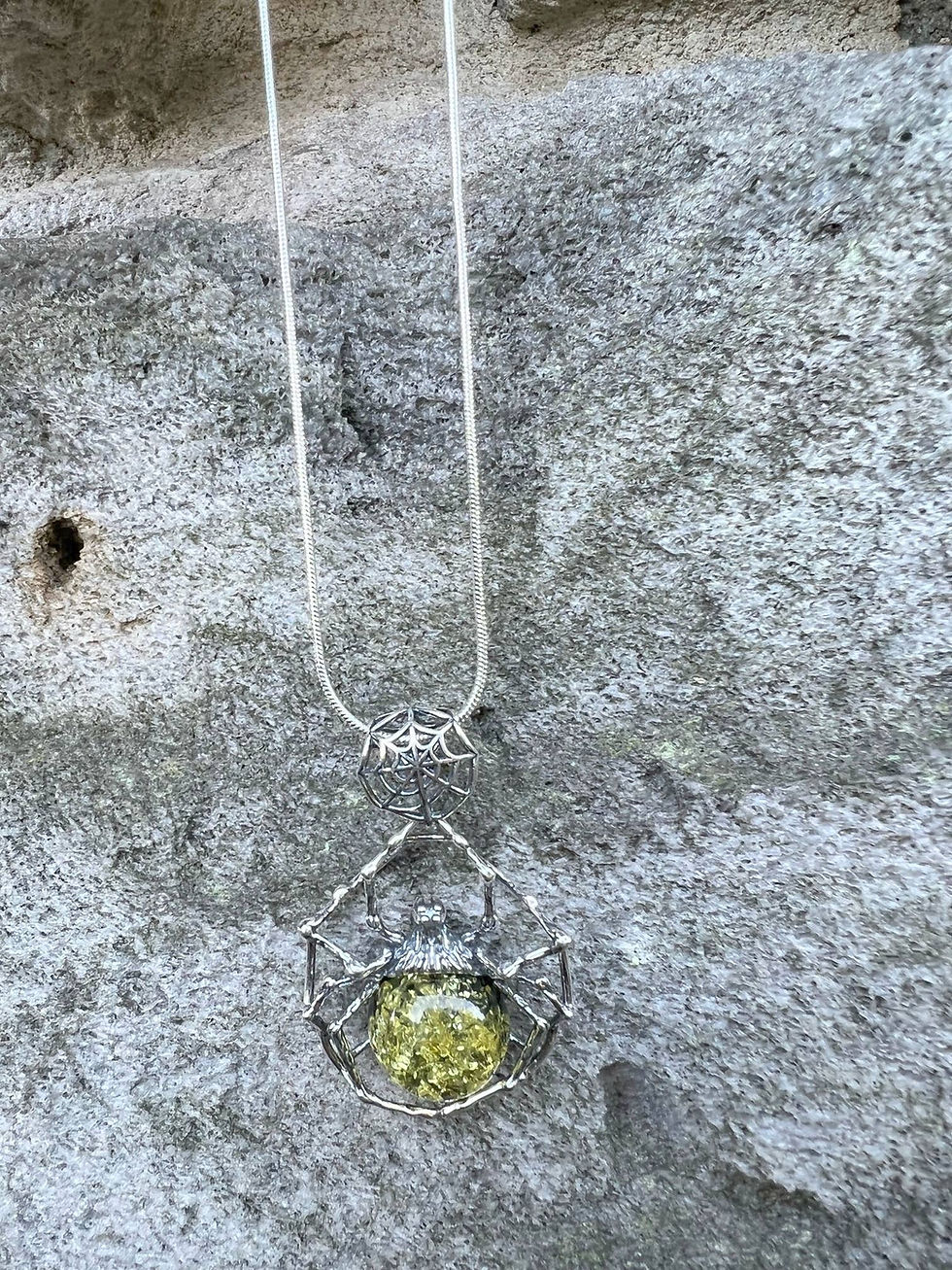 Thumbnail: Silver necklace with a green gemstone, hanging against a textured gray background.