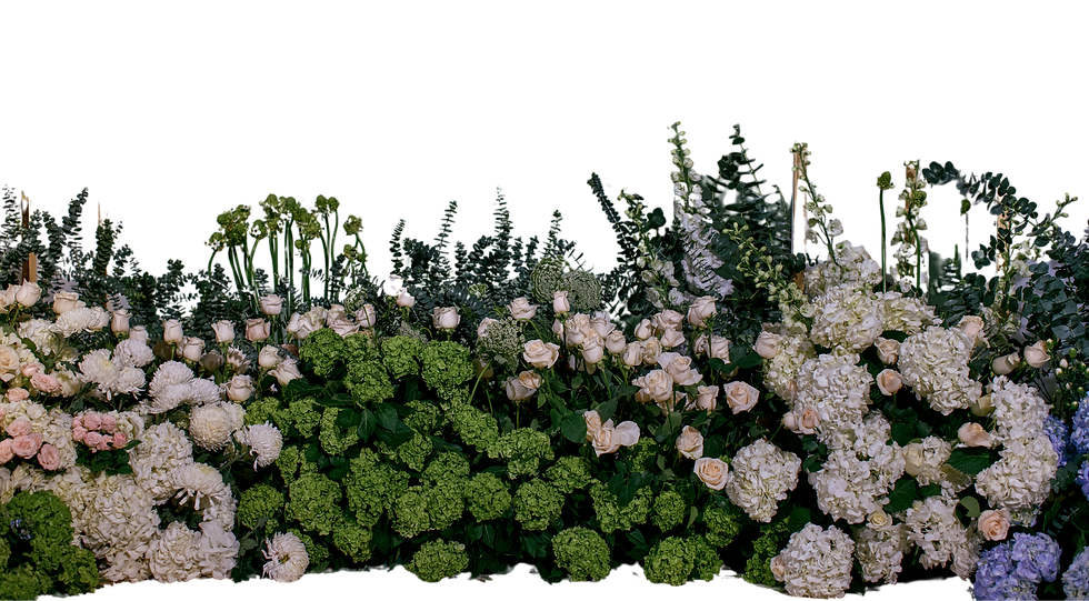 A lush arrangement of green and white flowers and foliage in front of large window panels.