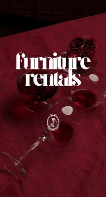 A group of wine glasses filled with a dark red liquid, one of which is tipped over on a deep red tablecloth.