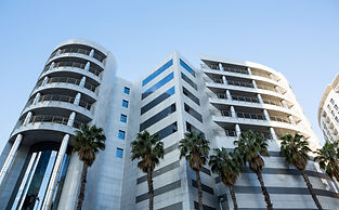 Modern white building with palm trees and blue sky backdrop DOT IT AE