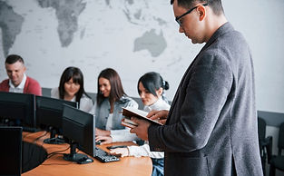 Manager reading report, team working with computers near world map background.
