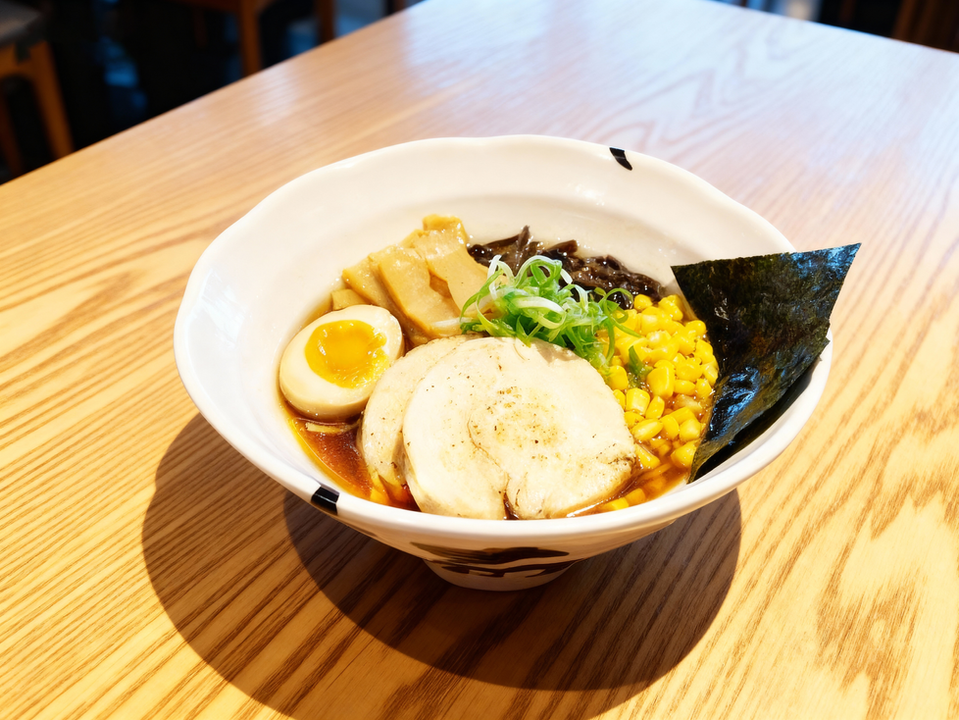 Delicious ramen bowl with corn, egg, and chicken in a restaurant setting.