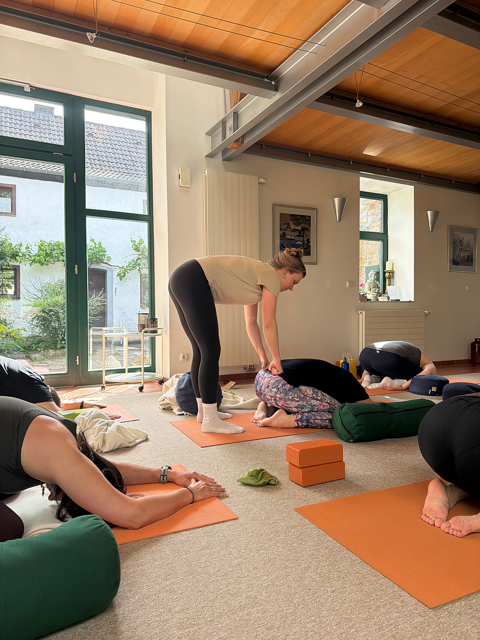 Yogalehrerin unterstützt Teilnehmerin während einer Yin Yoga Einheit beim EIFELGLÜCK Frauen Retreat in der Casa Inspira in der Eifel