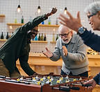3 senior men having fun Playing Foosball