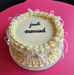Round yellow "just married" cake with ruffled frosting, white ribbons.
