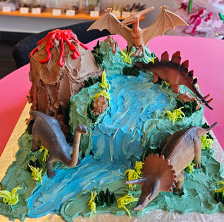 Volcano, waterfall, and dinosaur figures on a detailed themed birthday cake.