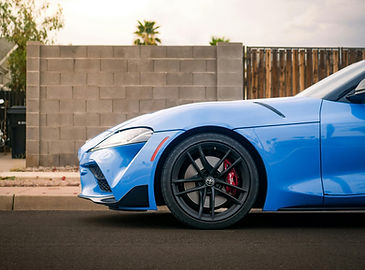 Black alloy rims on a sports car parked in sunlight