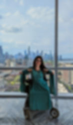 Jessica wearing a green sparkly gown with a view of the Chicago skyline behind her
