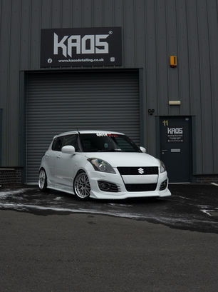 white Suzuki swift in front of Kaos Detailing studio