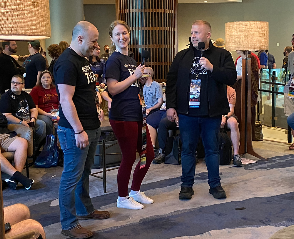 Innkeeper Hatch interviewing Sara and Omar from Wot Series in the lobby.