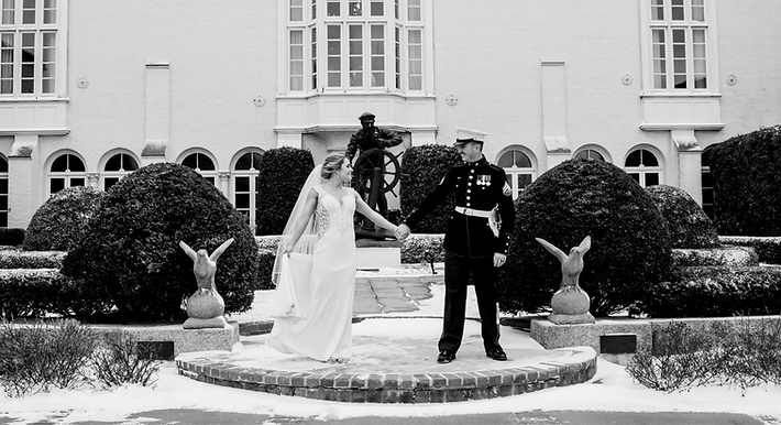 Black and white photo of bride and groom holding hands in front of their Michigan wedding venue Grosse Pointe Yacht Club | Wedding photographer Bearded Wolf Productions
