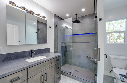 Modern bathroom remodel in San Diego with gray tile walk-in shower, LED lighting, glass enclosure, and quartz countertop vani
