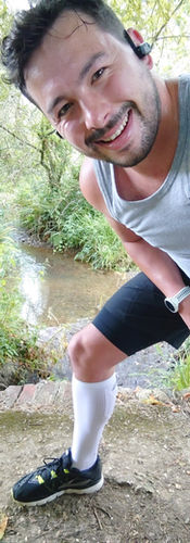 Cameron posing in his 2XU Vectr Cushion Full Length Socks by a river on a run on the Isle of Wight