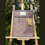Thumbnail: The Ailsa plum-framed notice board on a wooden easel with gold hooks and hanging floral keyrings.