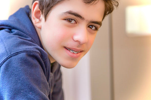 Preteen or Teen boy sits and smiles at camera