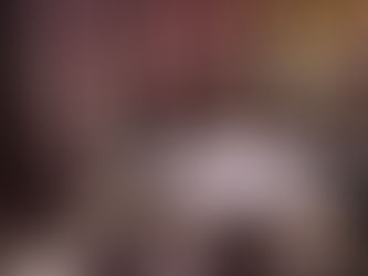 Elegant banquet in a cathedral with round tables, white tablecloths, candles, and a lit monogram on the floor. Tall archways and a warm ambiance.