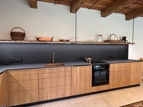 Kuchyň z biodesky, dubové dýhy s černou kompaktní pracovní deskou.