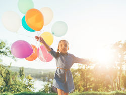 Girl running with coloured balloons