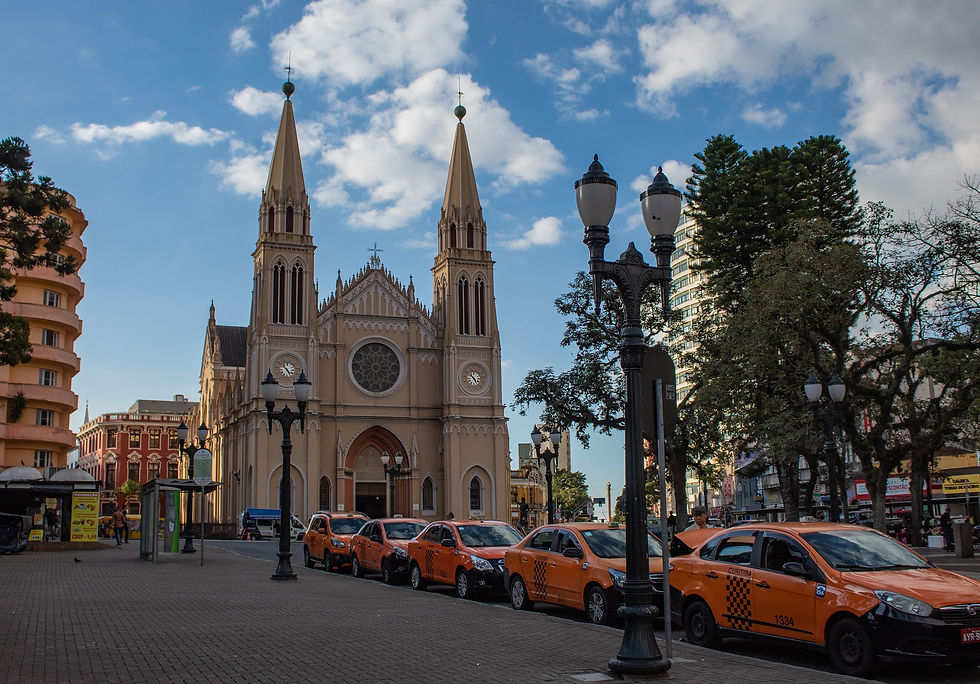 Obras arquitetonicas - Calcada com vários carros na lateral e com uma igreja rodeada por alguns predios