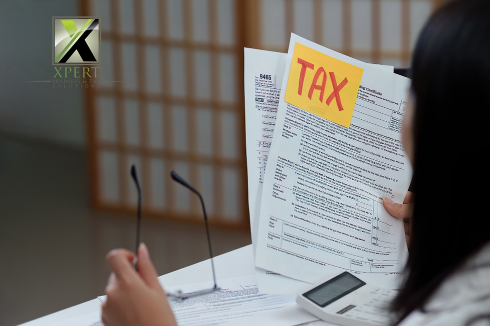 Person reviewing tax documents with a yellow note labelled “TAX,” holding paperwork at a desk with a calculator, representing tax preparation and financial review, branded with the Xpert Business & Tax Solutions logo.
