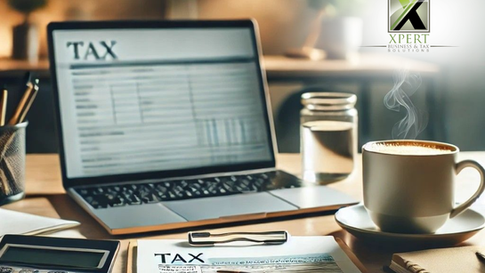 Alt text: A close-up shot of a workspace featuring a laptop displaying a tax spreadsheet, a calculator, a cup of coffee with steam rising, a glass of water, a pen, and a tax form, all arranged on a wooden desk. The logo for "XPERT Business & Tax Solutions" is visible in the corner.