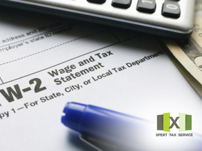 The image shows a W-2 form, which is a Wage and Tax Statement, commonly used by employees to report income and taxes withheld by their employer. The form is accompanied by a blue pen, a calculator, and a few dollar bills, indicating the process of reviewing or preparing for tax filing. This suggests the individual is organizing financial documents for tax-related purposes.