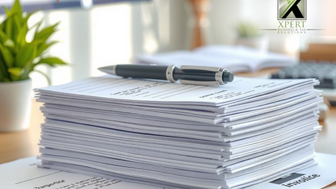 Stack of organised tax and financial documents on a desk with a pen placed on top, representing tax filing, record keeping, compliance paperwork, and business documentation in a professional office setting.