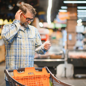 Man at grocery store looking at his receipt worriedly.