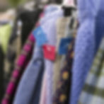 Close-up of patterned clothes on a rack with blue and red price tags, including $1, in a softly blurred shop setting.