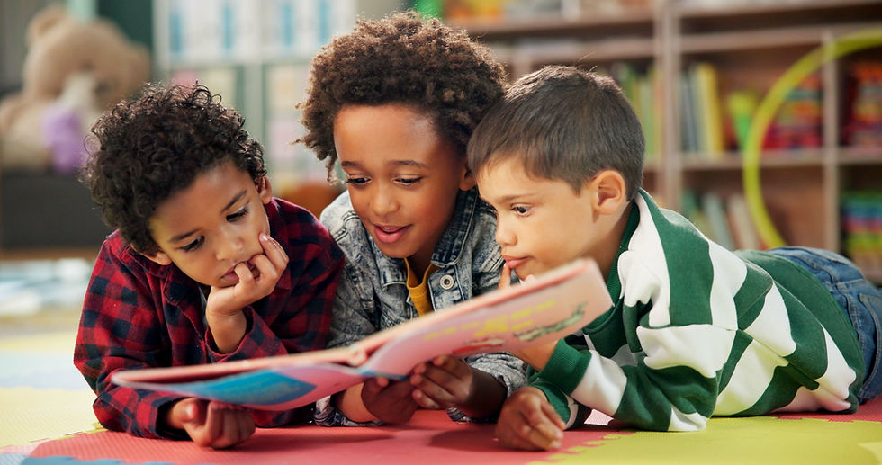 Three young children lay reading a book.