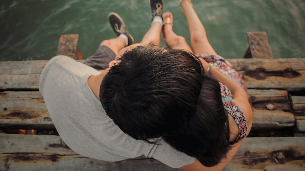 couple sitting by the water and hugging