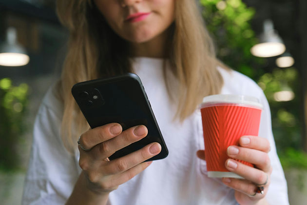 woman doing research on phone while drinking coffee