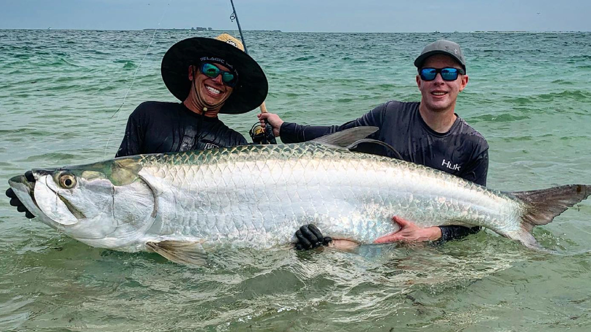 men holding tarpon in the water