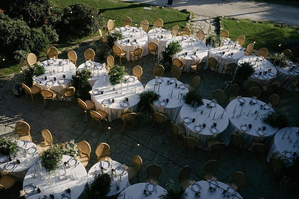 Aerial view of elegant wedding reception with round tables set on the stone courtyard of Castello di Petrata castle venue near Assisi, Umbria
