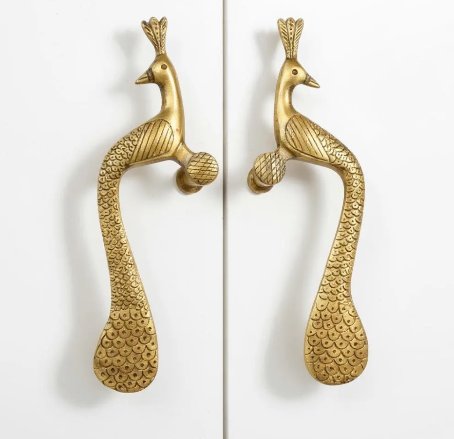 Thumbnail: Pair of solid brass peacock handles with ornate detailing and sculpted tail design mounted on white cupboard doors