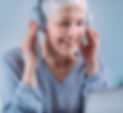 woman smiling and appearing happy while undergoing a hearing test with an audiologist, showcasing a positive experience with the diagnostic equipment.