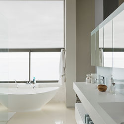 The image features a modern bathroom with a freestanding bathtub near a large window, a vanity with a sink and mirror, and a white minimalist color scheme. It emphasizes a clean and serene atmosphere with natural light enhancing the space.