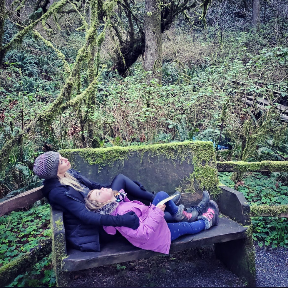 Woman and girl snuggling on mossy bench