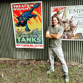Man standing next to WWII recruitment poster