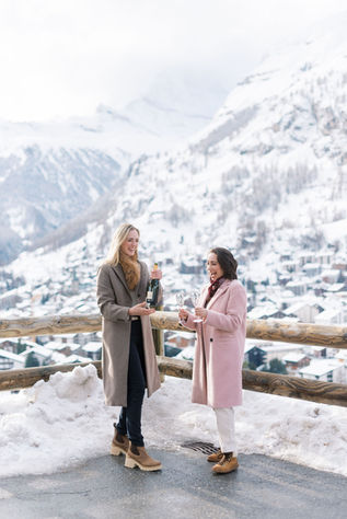 LGBTQ+ couple during winter engagement in Zermatt, Switzerland. Two women toast