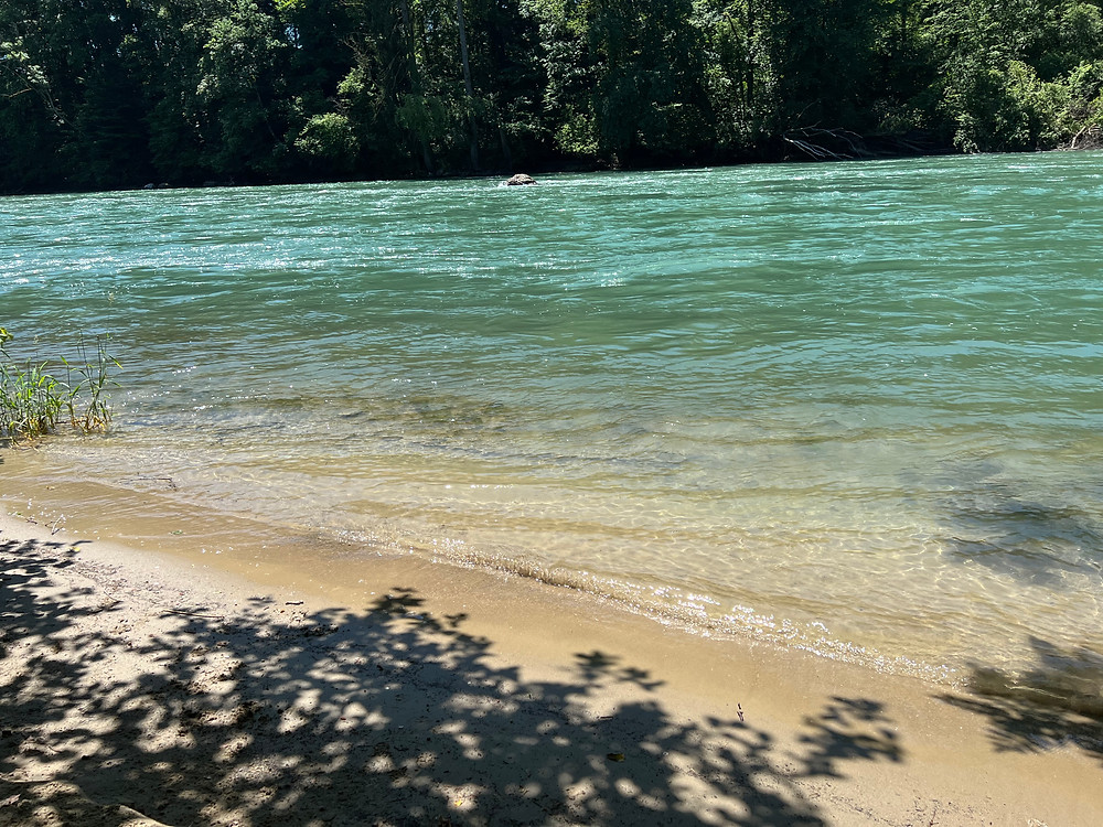 grünblaues Wasser und Sandstrand an einem Fluss